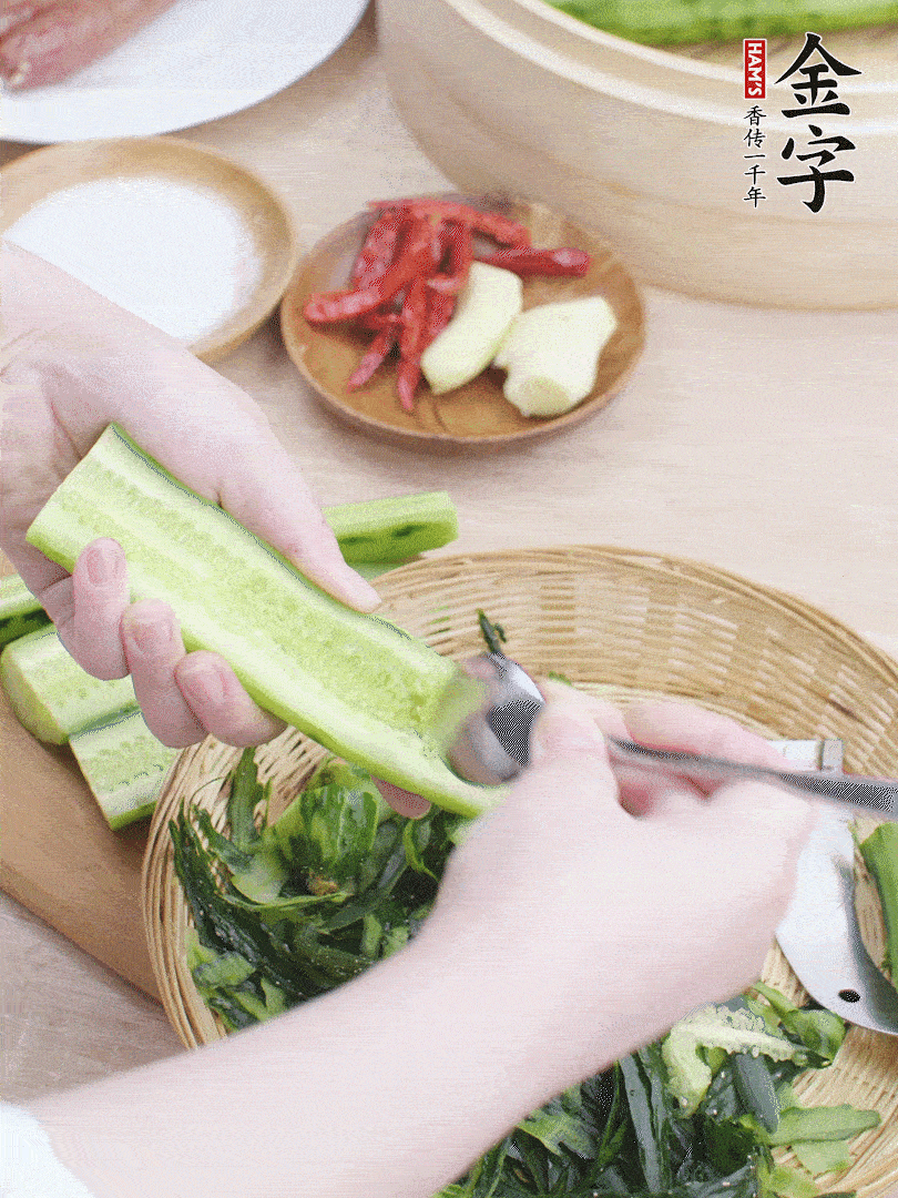 黃瓜削皮，對半切開，勺子挖去內(nèi)瓤，斜刀切片。青蒜斜刀切段。